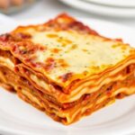 صحن لازانيا كلاسيكية بطبقات جبن وصلصة طازجة وملعقة خشبية