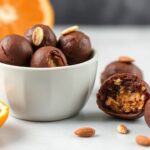 قطع شوكولاتة بالبرتقال الصحية مرصوفة على طبق مع قشر برتقال طازج