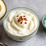Creamy taro pudding in a bowl garnished with coconut flakes and mint.