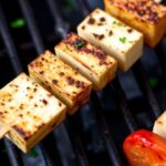 Grilled halloumi skewers with cherry tomatoes, peppers, and herbs on a rustic platter