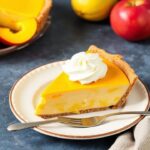 فطيرة مانجو كريمية استوائية على طاولة خشبية، لمسة كلاسيكية بطابع استوائي.