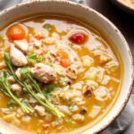 Cozy bowl of Turkey and Wild Rice Soup with herbs, vegetables, and creamy broth on a table.