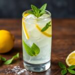 Glass of yuzu lemonade with sparkling bubbles, mint leaves, and fresh lemon zest garnish.
